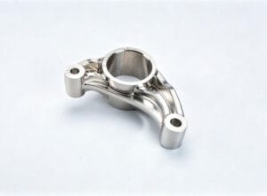 Precision 5-axis CNC machined Inconel superalloy rocker arm bracket with central precision bore, two end mounting lugs, and intricate sculpted curved surfaces