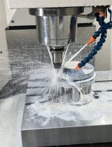Precision CNC milling services - vertical machining center milling a circular aluminum part with coolant flood, high-speed spindle and tight tolerance machining