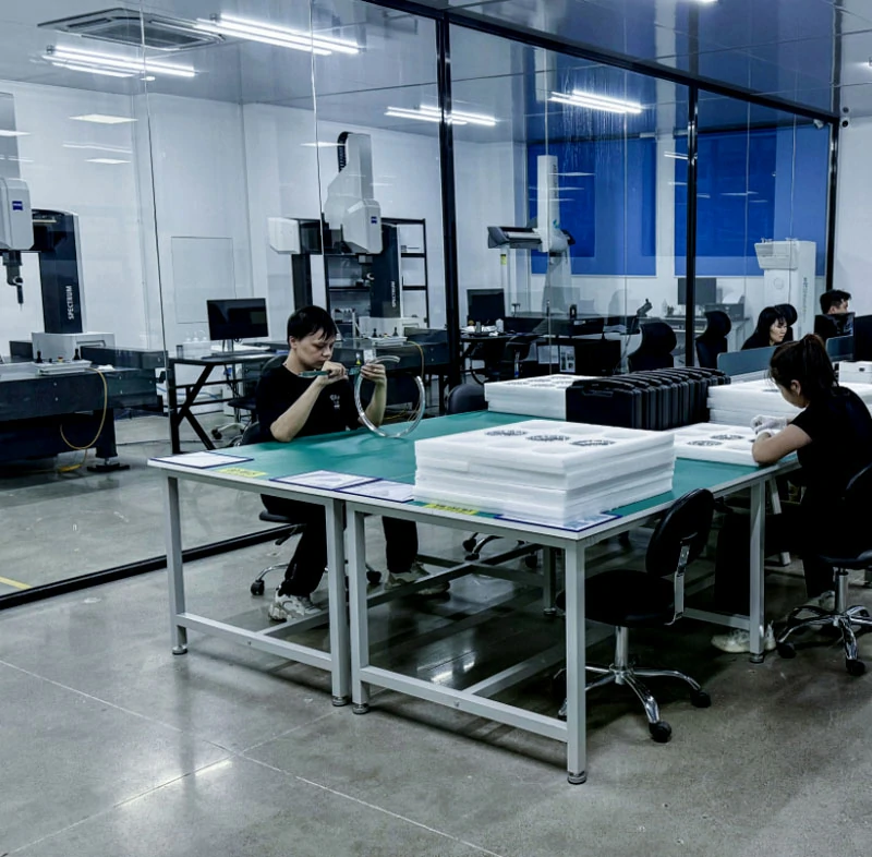 Clean quality control room with Zeiss coordinate measuring machine, inspector measuring machined metal ring with caliper at inspection bench