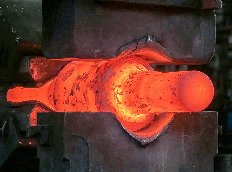 Large alloy steel stepped shaft undergoing closed-die hot forging in a forging workshop