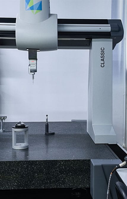 Close-up of Zeiss coordinate measuring machine with ruby touch probe above granite surface plate, inspecting precision machined part
