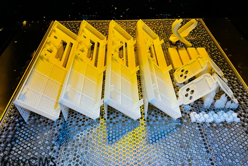 Finished SLA resin 3D printed parts on a build platform, white photopolymer prototypes